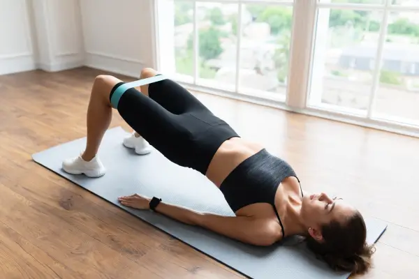 Exercício com faixa elástica e tapete de yoga, representando os melhores equipamentos de ginástica para fazer em casa.