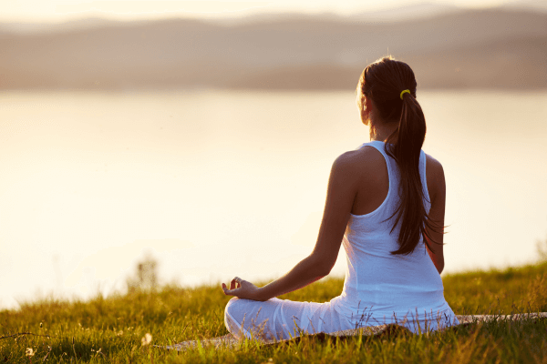 Transforme sua vida com meditação: 5 minutos que fazem a diferença – mulher meditando ao ar livre durante o pôr do sol