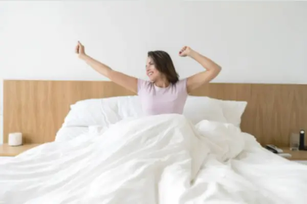 Mulher realizando alongamentos noturnos no quarto antes de dormir.